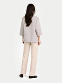 back view of a woman wearing a light gray poncho jacket and beige pants on a white background #color_dawn-blue