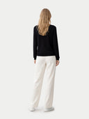 back view of a black sweater and white pants on a white background #color_black