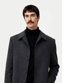 Man wearing a dark gray coat over a black turtleneck on a white background #color_charcoal
