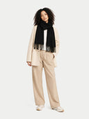 Woman wearing a black scarf, beige coat, and pants on a white background #color_black