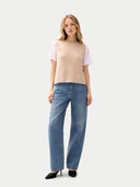 front view of a woman wearing a beige sleeveless sweater and blue jeans on a white background #color_beige