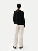 back view of a Person wearing a black sweater and white pants on a white background #color_black