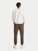back view of a person wearing a white sweatshirt and brown pants on a white background #color_cocoa