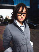 A woman in glasses and a grey CashmereTech puffer jacket on a city street