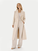 Woman wearing a long beige coat and pants on a white background #color_beige