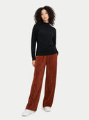 Person wearing a black sweater and brown pants on a white background #color_black