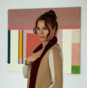 Anna von Griesheim in a cream cashmere cardigan and burgundy scarf in front of abstract paintings