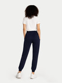 back view of a Person wearing navy jogger pants and a white t-shirt on a white background #color_navy