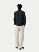 back view of a Person wearing a black turtleneck and beige pants on a white background #color_charcoal