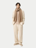 Person wearing a beige outfit with a scarf on a white background