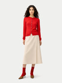 Woman wearing a red cardigan, beige skirt, and red socks on a white background #color_red
