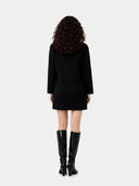 Back view of a person wearing a black dress and black boots on a white background #color_black
