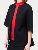 close up side view of a black poncho jacket over a red sweater #color_charcoal