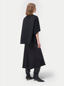 back view of a woman wearing a black poncho and skirt #color_charcoal