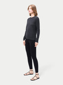 Side view of a woman wearing a dark gray long-sleeve top and black leggings on a white background #color_black