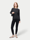 front view of a woman wearing a black long-sleeve top, holding a black handbag and leggings on a white background #color_black