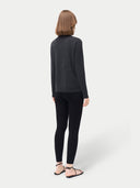 back view of a woman wearing a dark gray sweater and black leggings on a white background #color_black