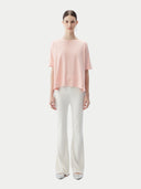 front view of a woman wearing a pink cashmere t-shirt and white pants #color_primrose-pink
