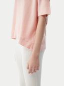 close up bottom side of a pink cashmere t-shirt with white ribbed pants #color_primrose-pink