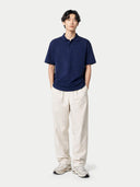 Person wearing a navy blue polo shirt and beige pants on a white background #color_navy