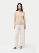 front view of a woman wearing a beige cardigan and light pink pants on a white background #color_beige
