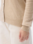 Close-up of a person wearing a beige cardigan and white pants on a light background #color_beige