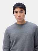 Person wearing a gray sweater and black beanie against a white background #color_black