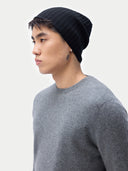 Person wearing a black beanie and gray sweater on a plain background #color_black
