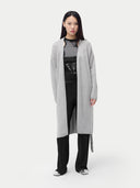Person wearing a gray cardigan over a black outfit on a white background