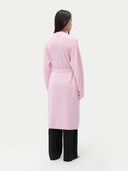 Person wearing a light pink robe against a plain background #color_almond-blossom