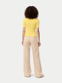 back view of a woman wearing a yellow top and beige pants on a white background #color_blazzing-yellow