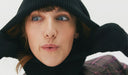 Person wearing a black knit hat and scarf against a white background