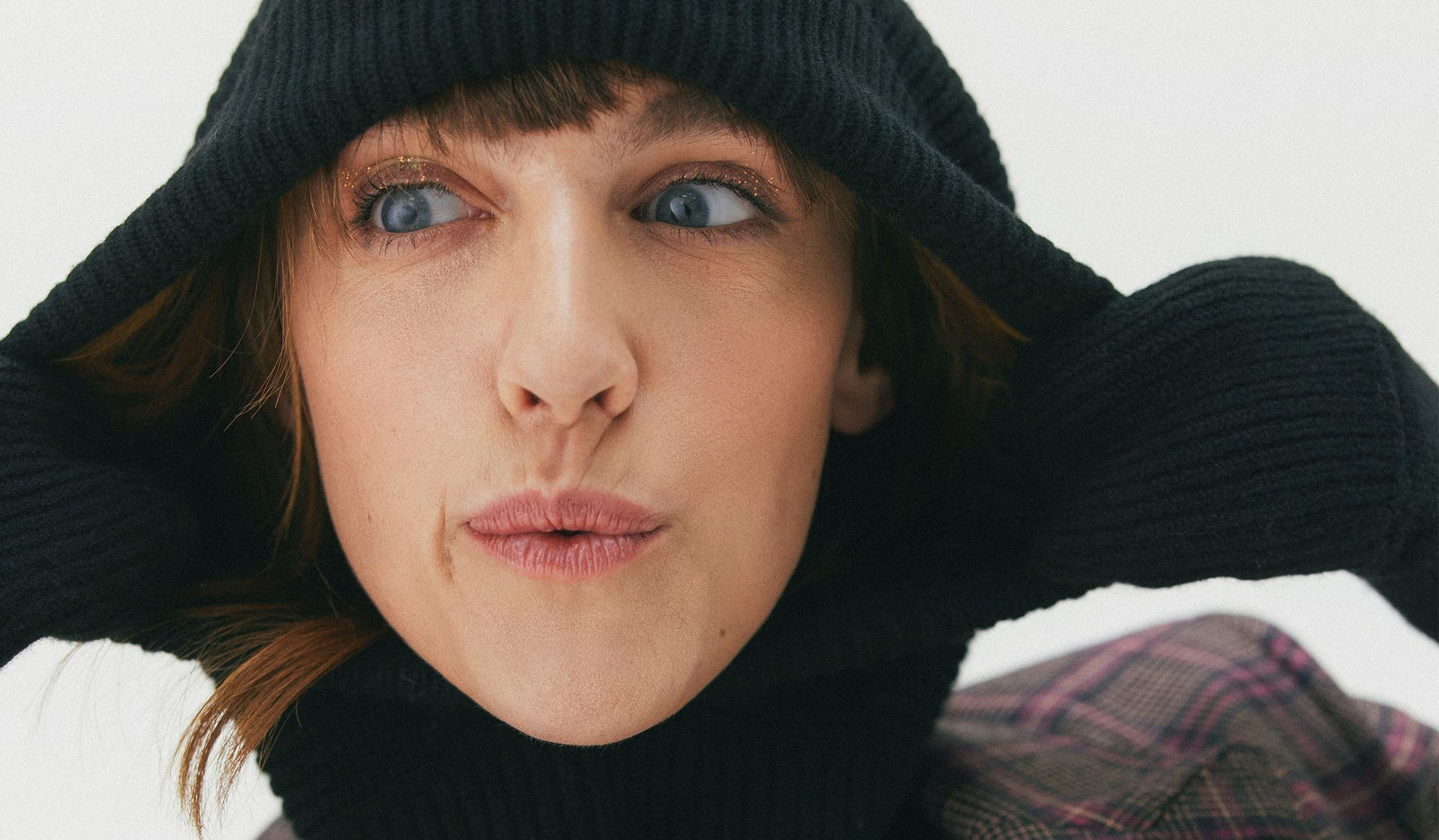 Person wearing a black knit hat and scarf against a white background