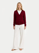 front view of a Woman wearing a burgundy v-neck cardigan and white pants on a white background #color_bordeaux