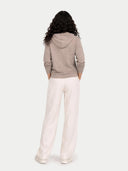 Back view of person wearing a light brown hoodie and white pants on a white background #color_taupe