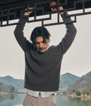 Man holding a traditional architectural element with a scenic background of mountains and water.