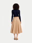 back view of a person wearing a navy long-sleeve top and beige skirt on a white background #color_navy-blazer