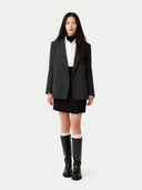 Person wearing a dark gray blazer, white shirt, black skirt, and black knee-high boots on a white background #color_charcoal