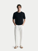Man wearing a black t-shirt and white pants on a white background #color_black
