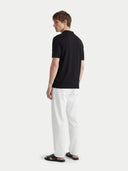 Side view of man wearing a black t-shirt and white pants on a white background #color_black