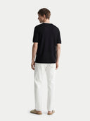 back view of a man wearing a black cashmere t-shirt and white pants on a white background #color_black