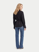 Woman standing back wearing a black long sleeves top and blue jeans on a white background #color_black