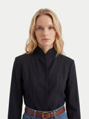 close up front view of a woman wearing a black mongolian v-neck traditional long-sleeve shirt with a plain background #color_black