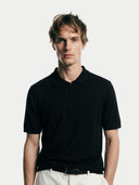 Close-up shot of Man wearing a black polo shirt against a white background #color_black