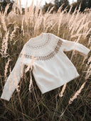 Cream Fair Isle cashmere jumper laid on tall autumn grass