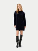 Woman wearing a black dress and black boots on a white background #color_navy-blazer