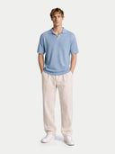 front view of a man wearing a light blue silk polo and white pants on a light gray background. #color_celestial-blue