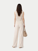 back view of a beige sleeveless top and wide-leg pants, holding a matching handbag on a white background. #color_off-white