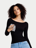 Woman wearing a black long-sleeve top and blue jeans, holding a silver clutch against a plain background #color_black