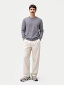 front view of a man wearing a gray sweater and white pants on a light gray background #color_dim-gray